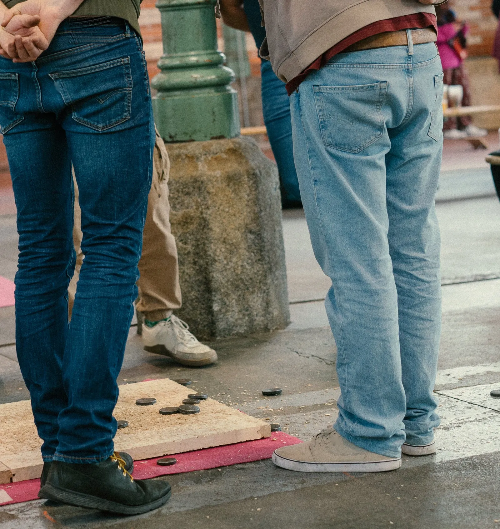 Deux joueurs de dos, les mains dans le dos, penchés sur une planche de palet, à la Halle Martenot